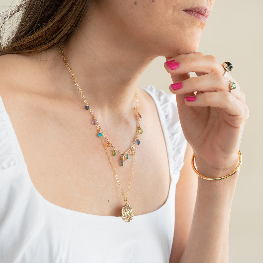 Woman wearing a colorful necklace and gold bracelet on a neutral background