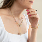 Woman wearing a colorful necklace and gold bracelet on a neutral background