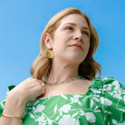 Woman wearing a green floral dress against a clear blue sky