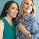 Two women standing close together against a light blue background