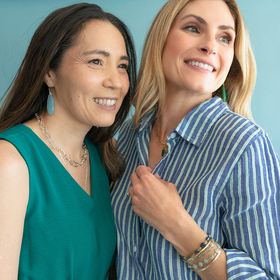 Two women standing close together against a light blue background