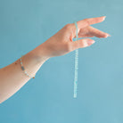Hand holding an aqua chalcedony necklace and wearing a matching bracelet against a blue background