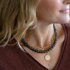 Close up of woman wearing smokey quartz gemstone necklace with layered gold necklaces