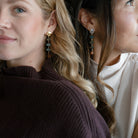Two women wearing gemstone statement earrings with labradorite and hessian garnet