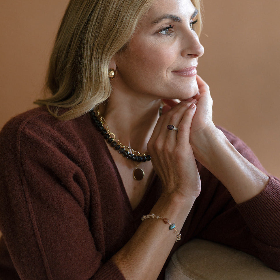 Woman in a brown sweater wearing a topaz and labradorite bracelet