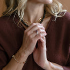 Woman wearing oval berry spinel mixed metal ring and a brown sweater