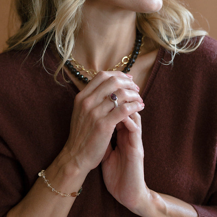Woman wearing oval berry spinel mixed metal ring and a brown sweater