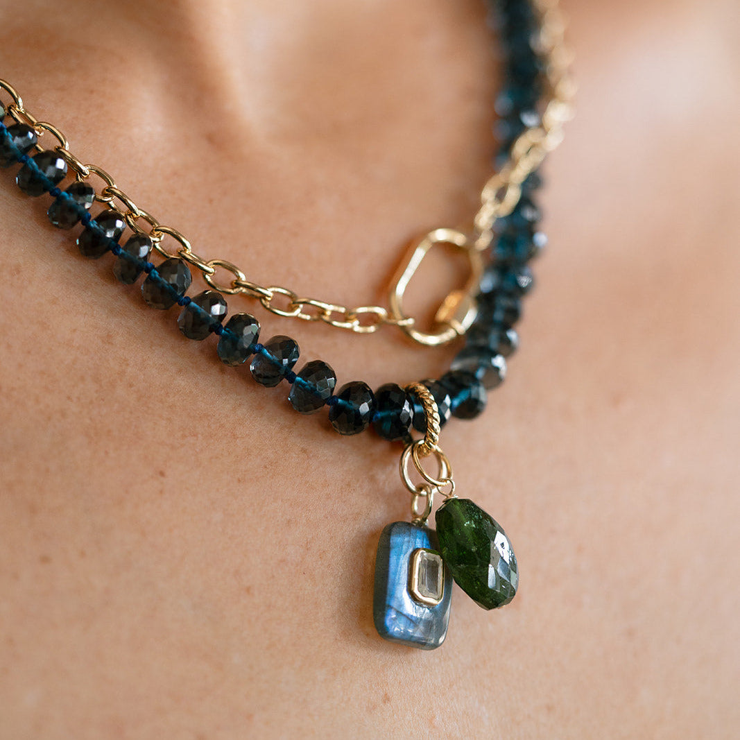 Close up of London Blue topaz necklace with layered charms