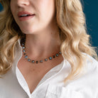 Woman wearing peacock pearl necklace and white shirt