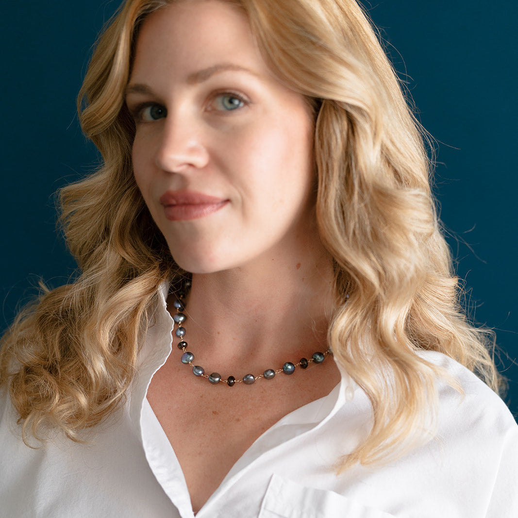 Woman wearing peacock pearl necklace and white shirt