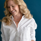 Woman wearing  small peacock pearl necklace and a white shirt