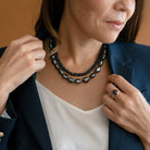 Woman wearing layered peacock pearls layered with a London Blue topaz necklace