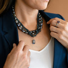 Woman wearing multiple peacock pearl necklaces and a navy blazer