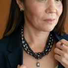Woman wearing gold hoop and necklace stack with navy blazer