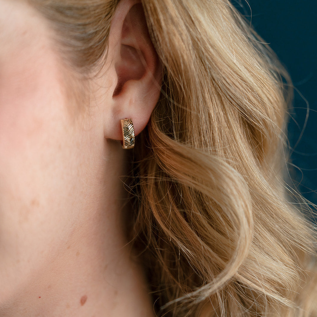 Woman wearing solid gold hoop on a blue background