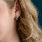Woman wearing solid gold hoop on a blue background