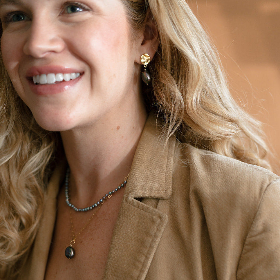 Woman in camel colored jacket at peacock pearl earring