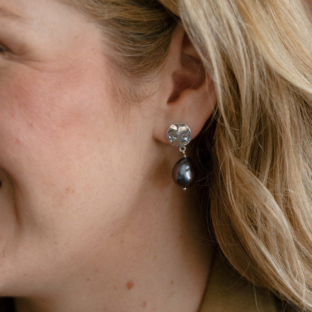 Woman in camel colored jacket at peacock pearl earring
