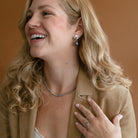 Woman wearing peacock pearl necklace and a camel colored blazer