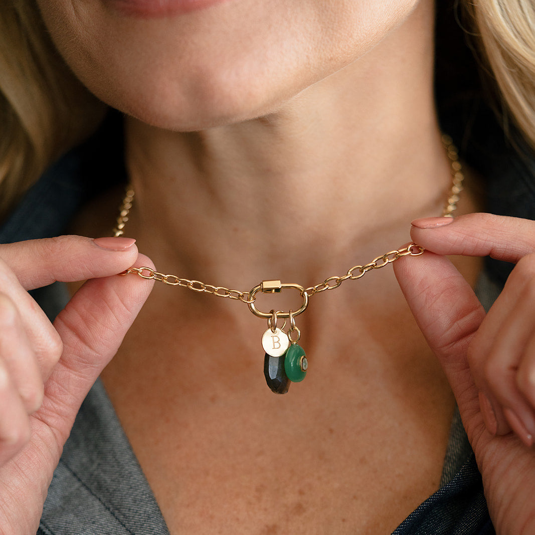 Woman wearing gold chain with charm carabiner and mixed charms