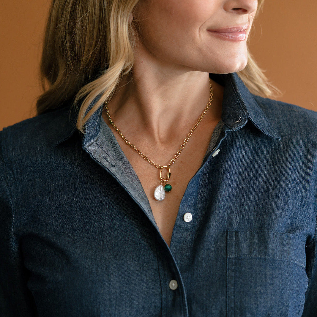 Woman wearing blue shirt and charm carabiner necklace