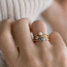 Close-up of a hand wearing multiple rings with gemstones on a neutral background