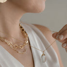 Close up of woman wearing layered gold necklaces and a silk top