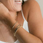 Woman wearing gold bracelets on a neutral background