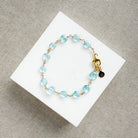 Blue quartz bracelet on a white card with a gold clasp on a beige surface