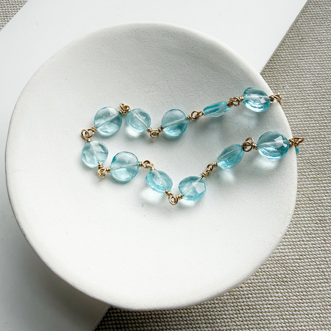 Blue quartz necklace on a white dish with a textured surface background
