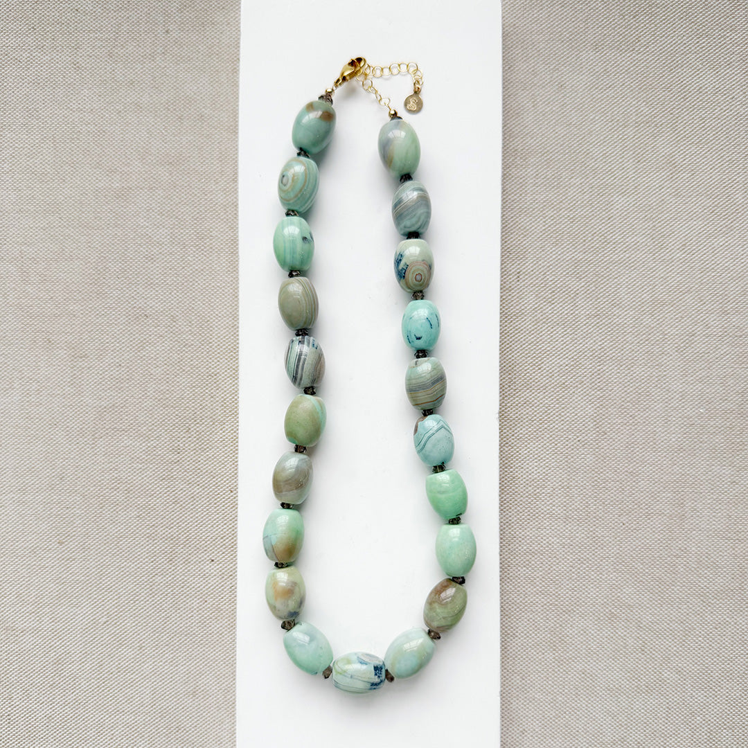 Necklace with teal agate beads on a white surface