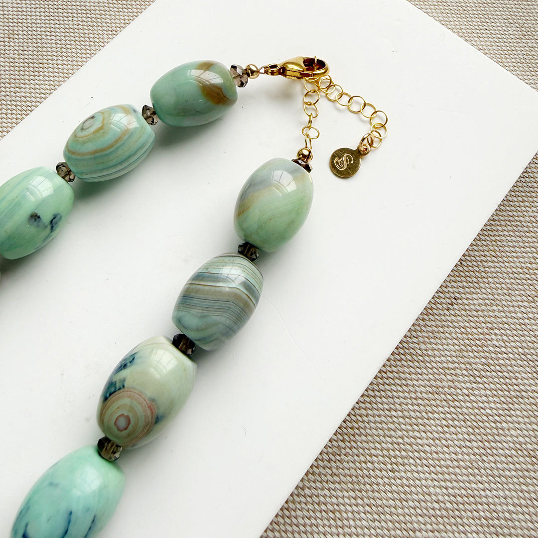 Clasp detail of necklace with teal agate beads on a white card