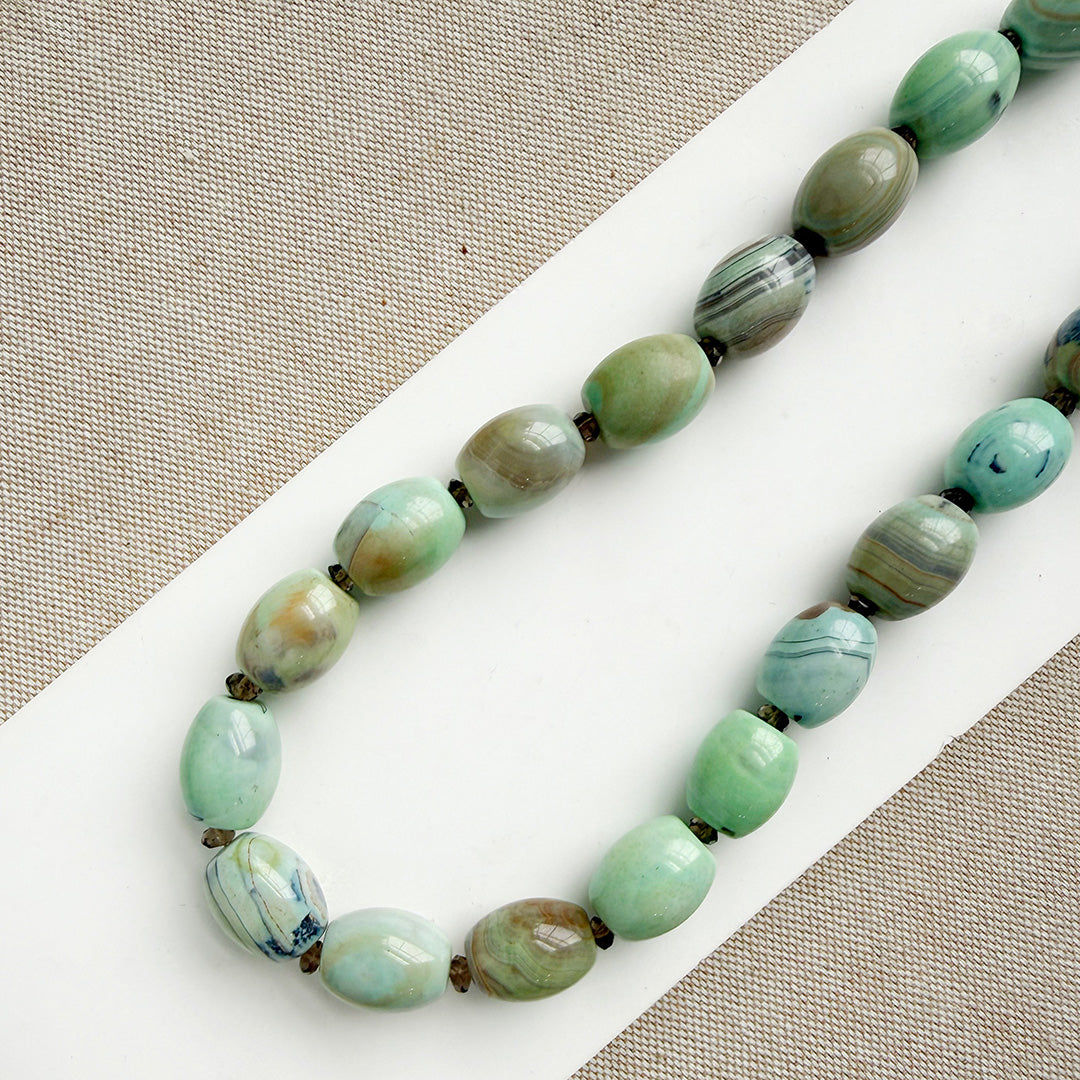 Necklace with teal agate beads on a white surface