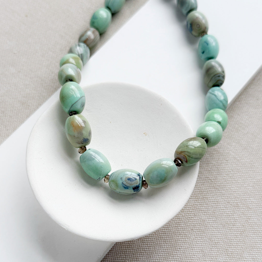 Necklace with teal agate beads on a white dish