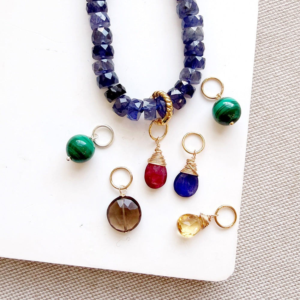 Mixed gemstone charms on a white background