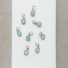 Teardrop shaped aqua chalcedony charms on a white plate