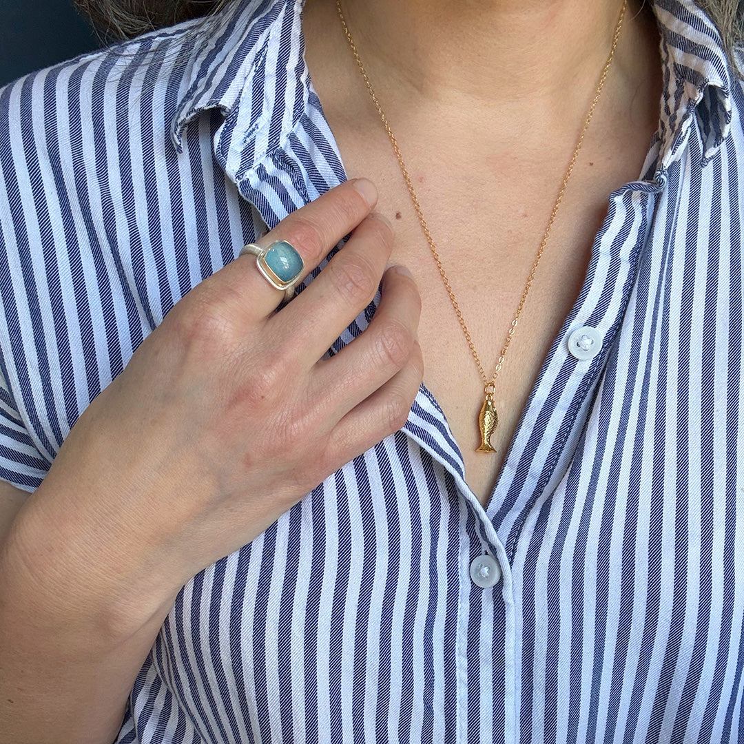 Hand wearing a smooth cushion cut mixed metal aquamarine ring 