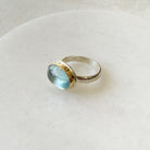 Oval aquamarine mixed metal ring on a white dish 