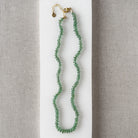Green Kyanite knotted necklace on a white dish with a neutral background
