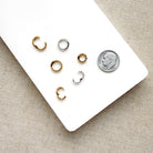 Charm ring enhancers in silver and gold on a white background with a dime for size reference