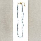 Knotted necklace with small round peacock pearls on a white dish