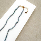 Knotted necklace with small round peacock pearls on a white dish