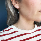 Close up of woman wearing tear drop shaped Golden Hills turquoise earrings in gold 