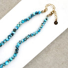 Clasp detail of  knotted Golden Hills turquoise necklace, draped over a white plate on a neutral textured surface.