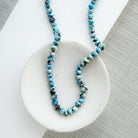 Necklace with Golden Hills turquoise beads on a white dish against a gray background