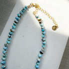 Necklace with Golden Hills turquoise beads on a white dish against a gray background