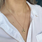 Gold beetle necklace with a pendant worn by a person in a white shirt.