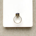 Side view of round berry spinel ring in a mixed metal setting, placed on a white dish