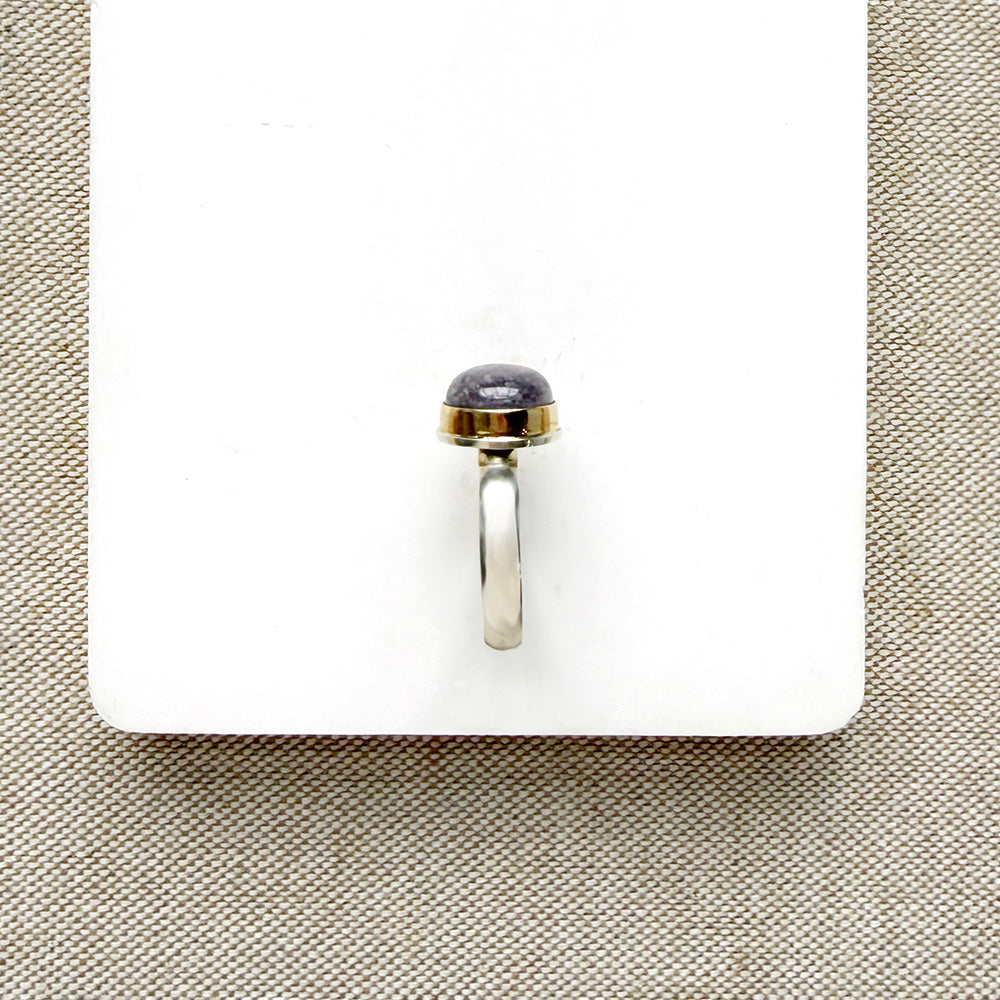 Side view of round berry spinel ring in a mixed metal setting, placed on a white dish