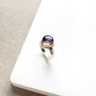 Round berry spinel ring in a mixed metal setting, placed on a white dish